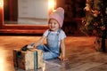 A little girl in the Christmas living room sits near the Christmas tree and opens gifts. Royalty Free Stock Photo