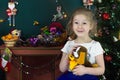 A little girl in the Christmas Studio. A little girl with blond hair smiles and holds a toy in her hands Royalty Free Stock Photo