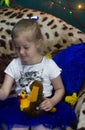 A little girl in the Christmas Studio. A little girl with blond hair smiles and holds a toy in her hands Royalty Free Stock Photo