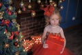 little girl at the Christmas tree in a red elegant dress with a box with gifts in her hands Royalty Free Stock Photo