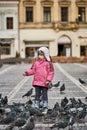 Little girl in a city square feeding pigeons Royalty Free Stock Photo