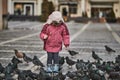 Little girl in a city square feeding pigeons Royalty Free Stock Photo