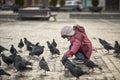 Little girl in a city square feeding pigeons Royalty Free Stock Photo