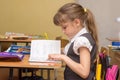 A little girl in class carefully reads a diary entry