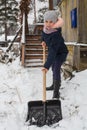 Little girl cleans snow to shovel near the country house. Royalty Free Stock Photo