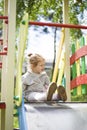 The little girl climbed onto a children slide on a playground for children and is very happy to play Royalty Free Stock Photo