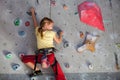 Little girl climbing a rock wall indoor.