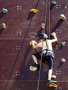 Little girl climbing a vertical rock wall with helmet on her