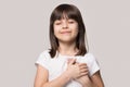 Little girl closed eyes hold hand on chest feels gratitude Royalty Free Stock Photo