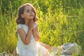 Little Girl closed her eyes, praying in a field during beautiful sunset. Hands folded in prayer concept for faith