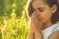 Little Girl closed her eyes, praying in a field during beautiful sunset. Hands folded in prayer concept for faith Royalty Free Stock Photo