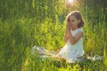 Little Girl closed her eyes, praying in a field during beautiful sunset. Hands folded in prayer concept for faith Royalty Free Stock Photo