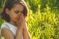 Little Girl closed her eyes, praying in a field during beautiful sunset. Hands folded in prayer concept for faith Royalty Free Stock Photo