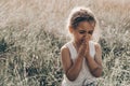 Little girl closed her eyes praying at sunset. Hands folded in prayer concept for faith, spirituality and religion. Hope, concept. Royalty Free Stock Photo