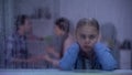 Little girl closing ears on rainy day, parents quarrelling in room, conflict Royalty Free Stock Photo