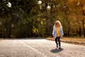 Little girl in coat in autumn plays with toy car on remote control in Park Royalty Free Stock Photo