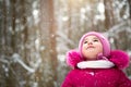 Little girl in the cold looks at the snow from the sky. Winter, walk the baby in the open air, snow. Warm clothing, knitted hat,