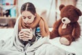 Little girl with cold in scarf and blanket with hot beverage in hands at home. Royalty Free Stock Photo