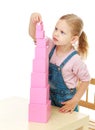 Little girl collects the pink pyramid. Royalty Free Stock Photo