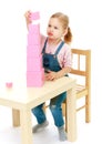 Little girl collects the pink pyramid. Royalty Free Stock Photo