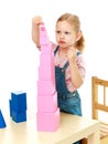 Little girl collects the pink pyramid. Royalty Free Stock Photo