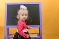 Little girl with colored chalk on the background of a children school board. The concept of preschool education for children Royalty Free Stock Photo