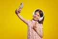 Little girl in colorful polo shirt taking selfie while listening to music Royalty Free Stock Photo