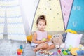 Little girl in colorful wigwam with toys. child plays with colorful toy blocks. Developing and creative toys and games for young c Royalty Free Stock Photo