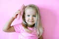 Little girl combing her hair. Beauty and childhood concept. Girl on a pink isolated background combing her hair with a pink comb Royalty Free Stock Photo