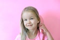 Little girl combing her hair. Beauty and childhood concept. Girl on a pink isolated background combing her hair with a pink comb Royalty Free Stock Photo