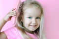 Little girl combing her hair. Beauty and childhood concept. Girl on a pink isolated background combing her hair with a pink comb Royalty Free Stock Photo