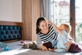 Little girl combs her laughing mother while sitting on the bed next to a lying cat Royalty Free Stock Photo