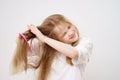 little girl combs tangled hair. white background.