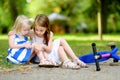 Little girl comforting her sister after she fell while riding her scooter Royalty Free Stock Photo