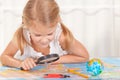 Little girl considering a world map with a magnifying glass