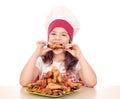 Little girl cook eating chicken drumstick