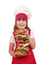 Little girl cook hold dish with tall sandwich
