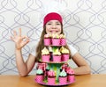 Little girl cook with tasty muffins and ok hand sign Royalty Free Stock Photo