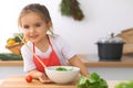 Little girl cooking in the kitchen. Kid slicing and mixing tomatoes and greenery. Concept of healthy meal or tasty Royalty Free Stock Photo