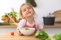 Little girl cooking in the kitchen. Kid slicing and mixing tomatoes and greenery. Concept of healthy meal or tasty Royalty Free Stock Photo