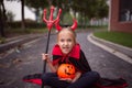 Little Girl in costume of devil with red horns in park. Happy Halloween concept Royalty Free Stock Photo