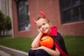 Little Girl in costume of devil with red horns in park. Happy Halloween concept Royalty Free Stock Photo