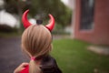 Little Girl in costume of devil with red horns in park. Happy Halloween concept Royalty Free Stock Photo