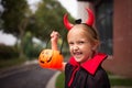 Little Girl in costume of devil with red horns in park. Happy Halloween concept Royalty Free Stock Photo