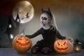 Little girl in a costume of witch posing with pumpkins over fairy background. halloween Royalty Free Stock Photo