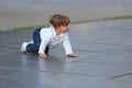 Little girl crawls on marble slabs outdoors in summer