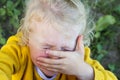 little girl cries, covering face with hands. injured child runs to mother for help. Close up portrait of crying little