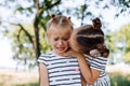 A little girl cries in the park, her older sister calms her down and kisses her