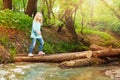 Little girl crossing log bridge in the forest