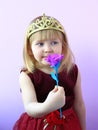 Little girl in crown smelling flower. Child in beautiful dress smiling